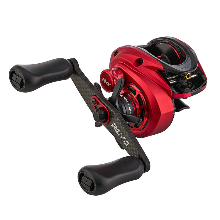 A red and black fishing reel with dual handles and various adjustment knobs is shown against a white background.