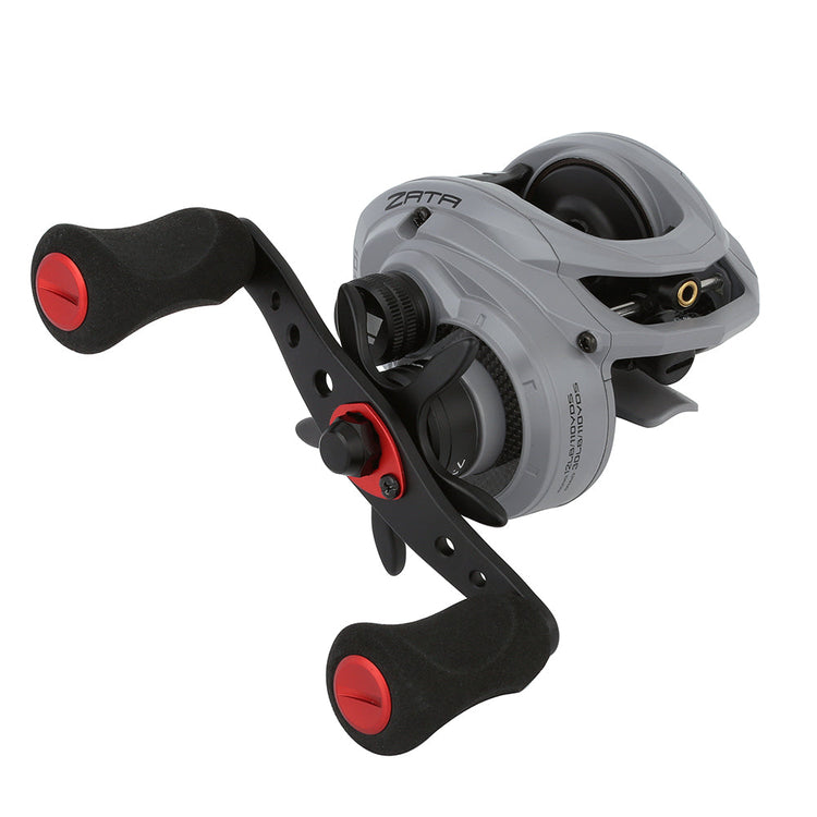 A close-up of a gray and black fishing reel with red accents. The design includes two red handles and various dials and mechanisms, providing a modern and sleek appearance.