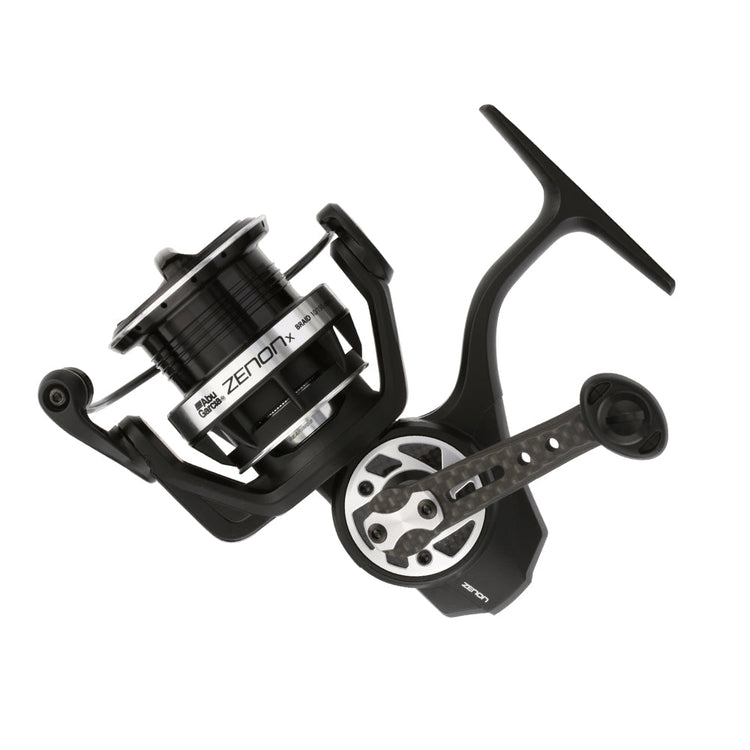 A black and silver fishing reel with the word "ZENON" on the side. The reel features a textured handle and a spool with visible line.