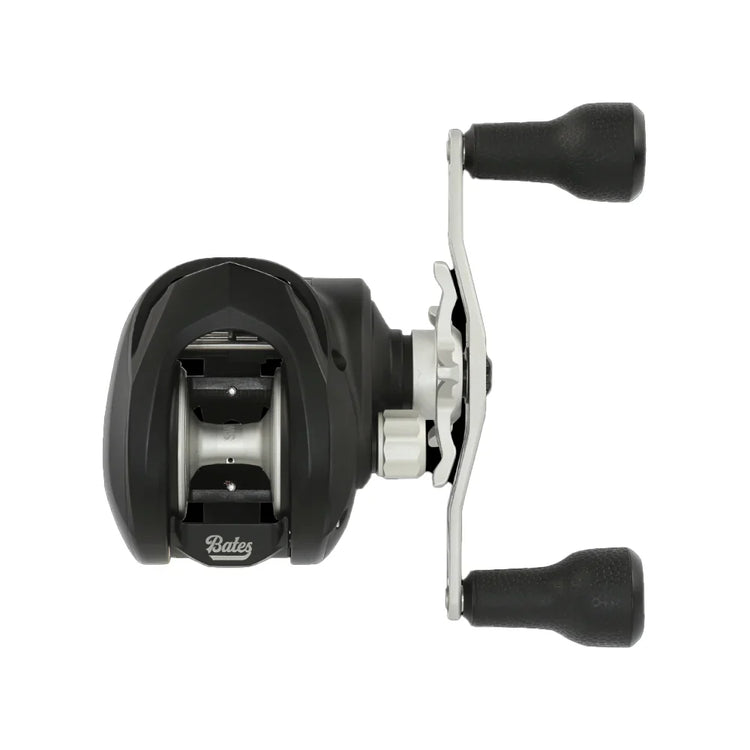 Top view of a black and silver baitcasting fishing reel with two black rubber handles. The brand name "Bates" is visible on the body. The reel is designed for precision casting.