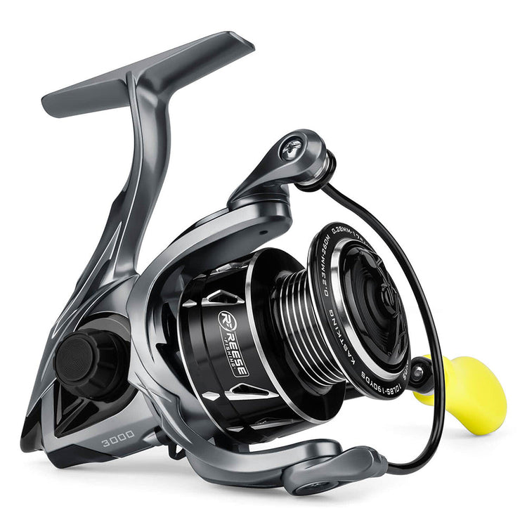 A modern fishing reel with a sleek metallic design. It has a smooth black and silver finish, a spool with visible line guides, and a yellow handle knob. The reel is labeled "3000" and "Reebs.