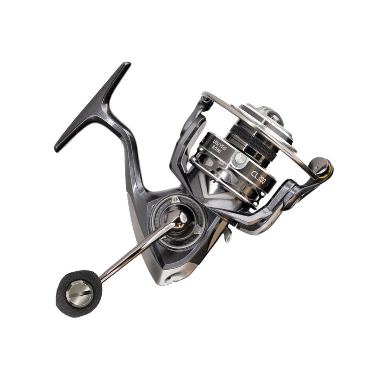 Close-up of a black and silver fishing reel with a modern design, featuring a crank handle and labeled parts. The reel is isolated on a white background, showcasing its intricate mechanical details.