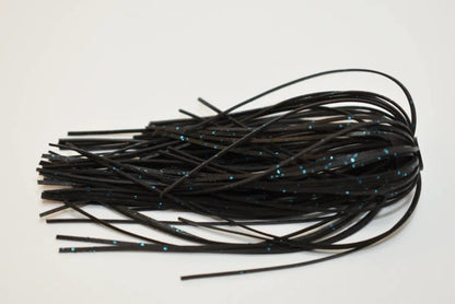 A bundle of black fishing skirt strands from the Accent River Special Spinnerbaits, infused with small blue glitter specks, is fanned out on a white surface.