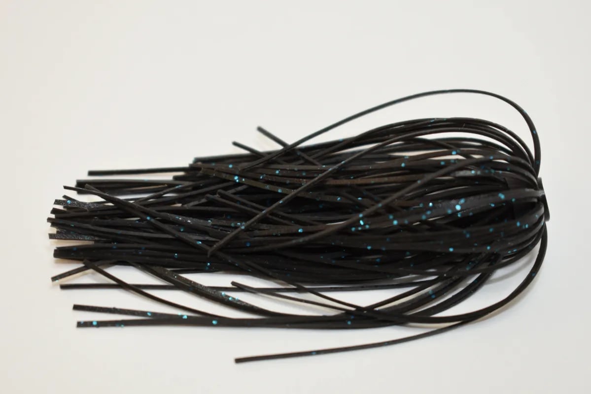 A bundle of thin, black plastic strands scattered on a white surface resembles the dynamic movement of Accent River Special Spinnerbaits by Accent. The shiny strands with small blue specks mimic the effect that lures bass in professional Bassmaster Classic tournaments.