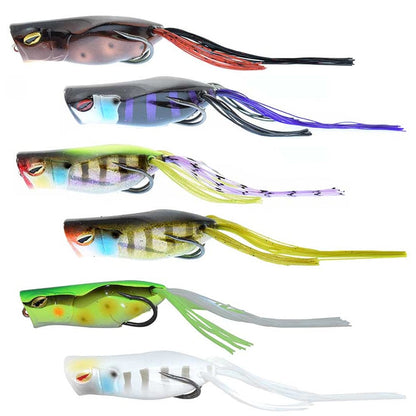 The Jackall Gavacho Frog lures, ideal for bass fishing, come in six colors: brown, red, purple, green, and white. They have fringed tails and curved hooks for long-distance casting and are arranged in two vertical rows.