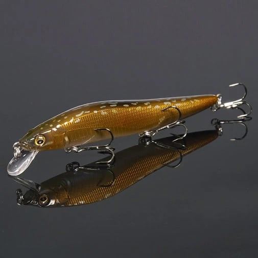 The Megabass Vision 110 Jr. Jerkbait is a realistic fishing lure with a shiny brown-gold body, black markings, and two treble hooks. It includes a transparent lip and the Multiway Moving Balancer System for lifelike motion against a reflective black surface.