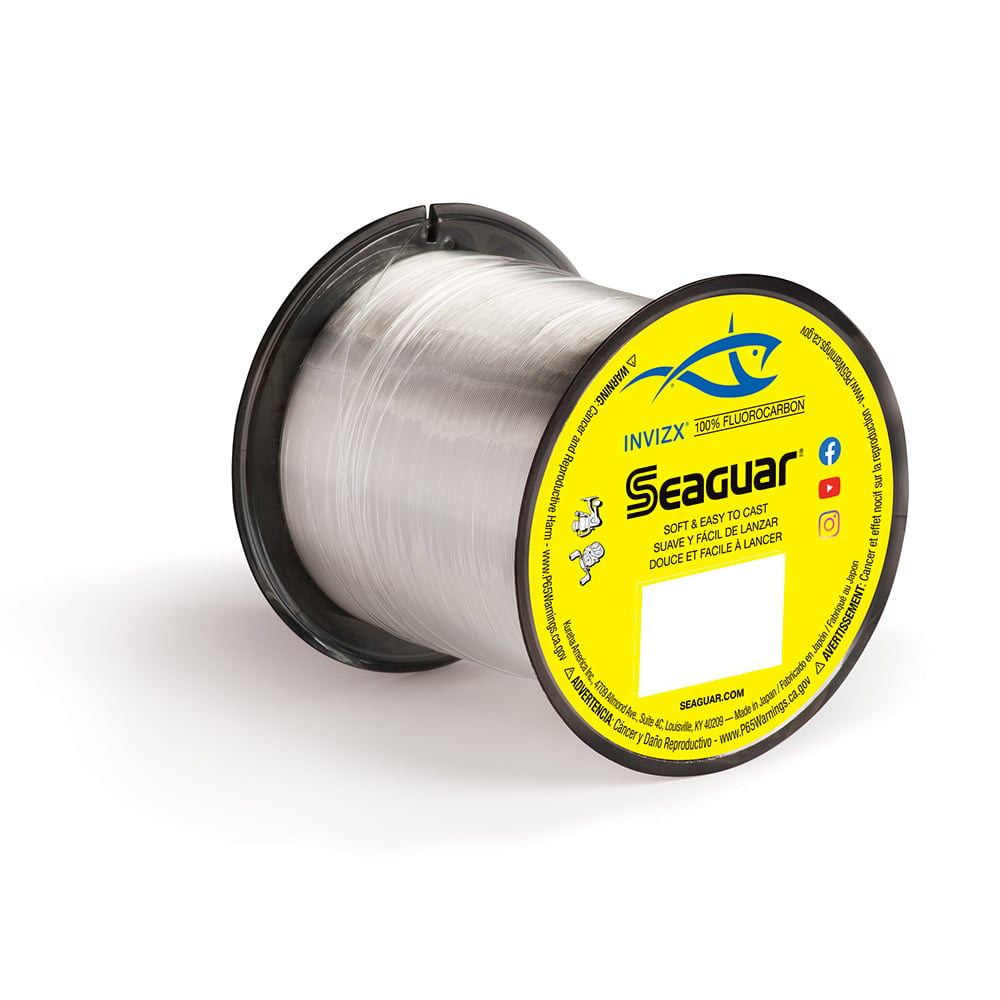 A spool of Seaguar's InvizX Fluorocarbon Line comes with a yellow label adorned with blue fish graphics. The multilingual label emphasizes its superior sensitivity. The spool is angled to display the clear line coiled around it.