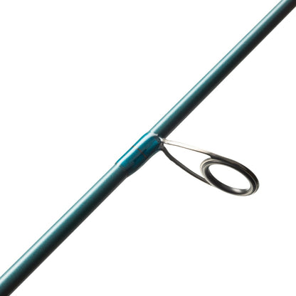 Close-up of a fishing rod guide on the St. Croix Mojo Inshore Spinning Rod 7'11" Heavy Moderate Fast (JIS711HMF) by americanlegacyfishing, featuring a sleek metallic loop attachment on a blue-green rod. This saltwater rod is engineered to direct the fishing line efficiently, ensuring smooth casting and retrieval even in challenging sea conditions.