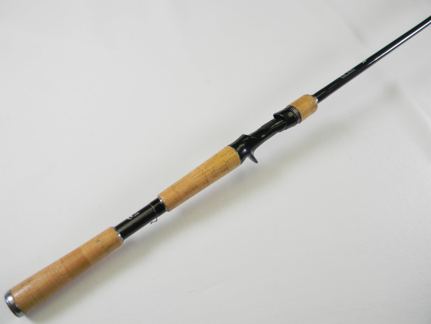 On a white background rests a Daiwa BLX LG731MLFB 7'3" Medium Light casting rod in excellent condition, showcasing a cork handle and black reel seat with graceful tapering for optimal casting. Trade your used gear for store credit with our Rod and Reel Trade-In Program.