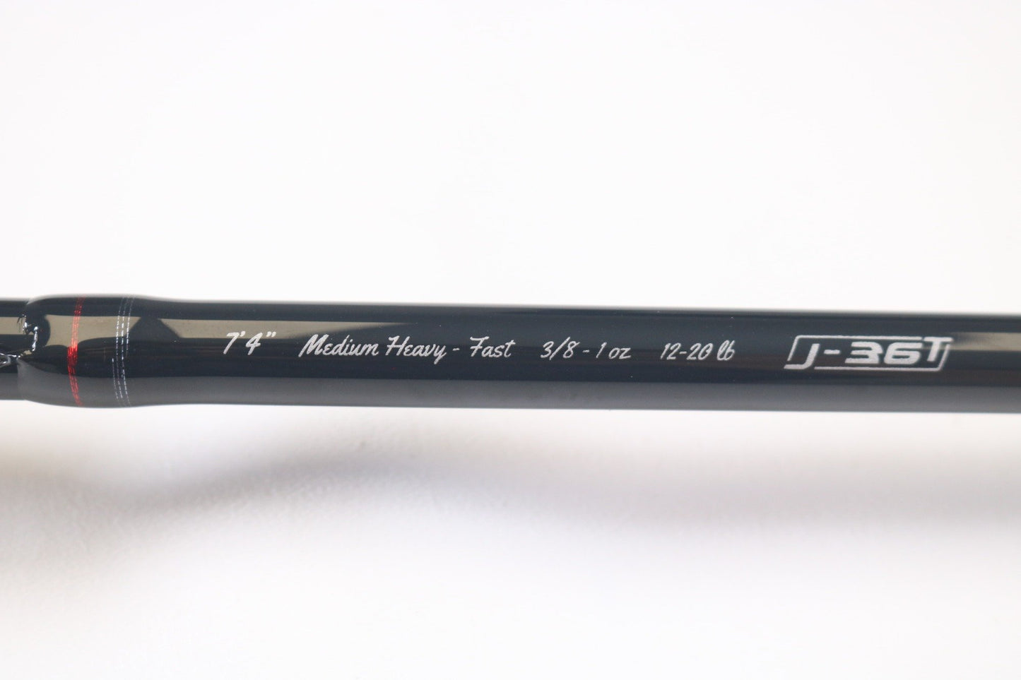 Close-up of a 13 Fishing Meta MTGC74MH 7'4" Medium Heavy Casting Rod: Specs - Fast action, 3/8-1 oz lure weight, and 12-20 lb line weight. It's black with red accents near the handle. Exchange used gear or explore our Rod and Reel Trade-In program for great deals!.