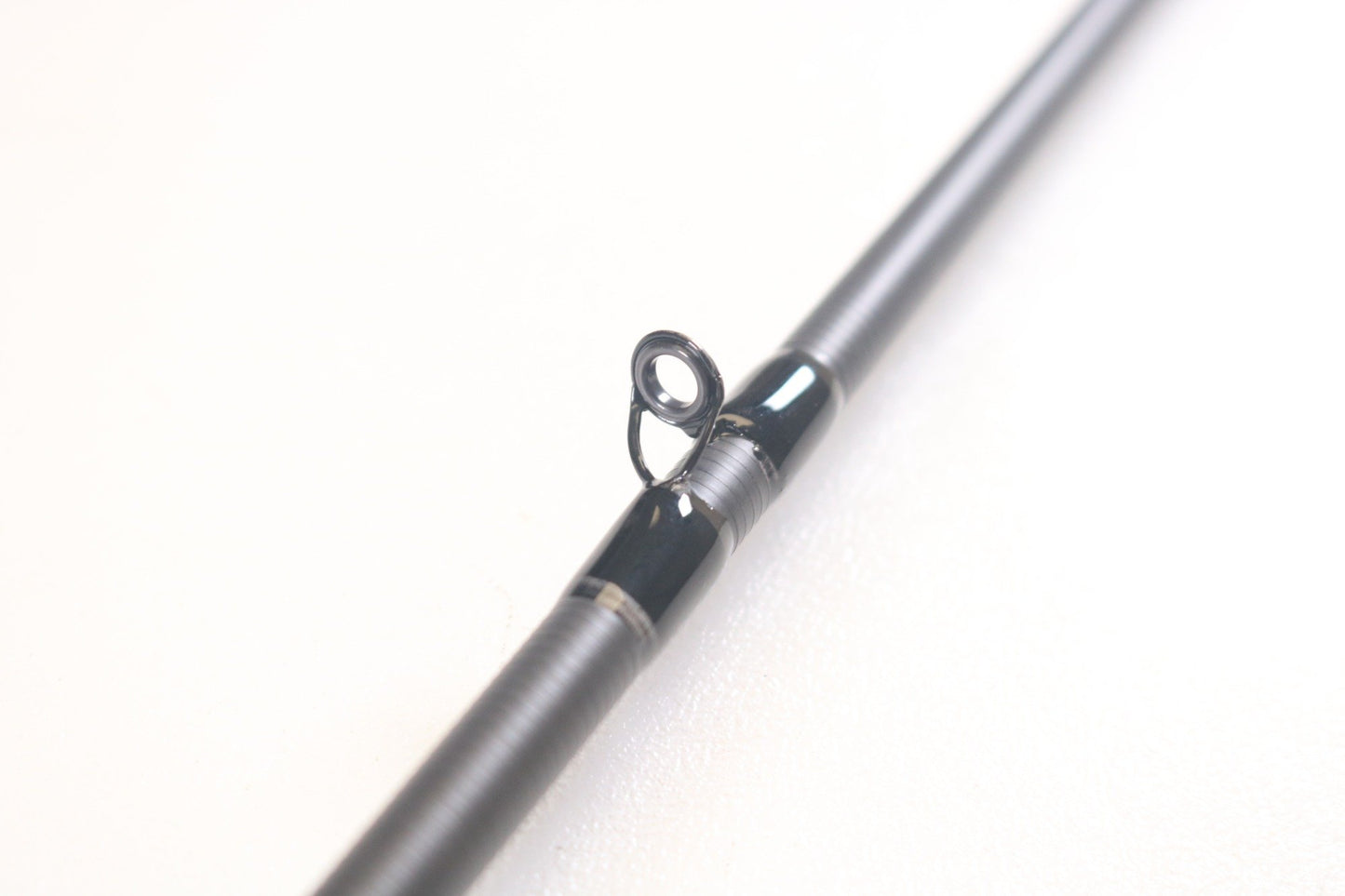 A close-up of the 13 Fishing Meta MTGC74MH 7'4" Medium Heavy used casting rod shows a single guide loop. The sleek, metallic gray finish is complemented by dark securing bands. Perfect for our Rod and Reel Trade-In program offering store credit, it's set against a plain white background.