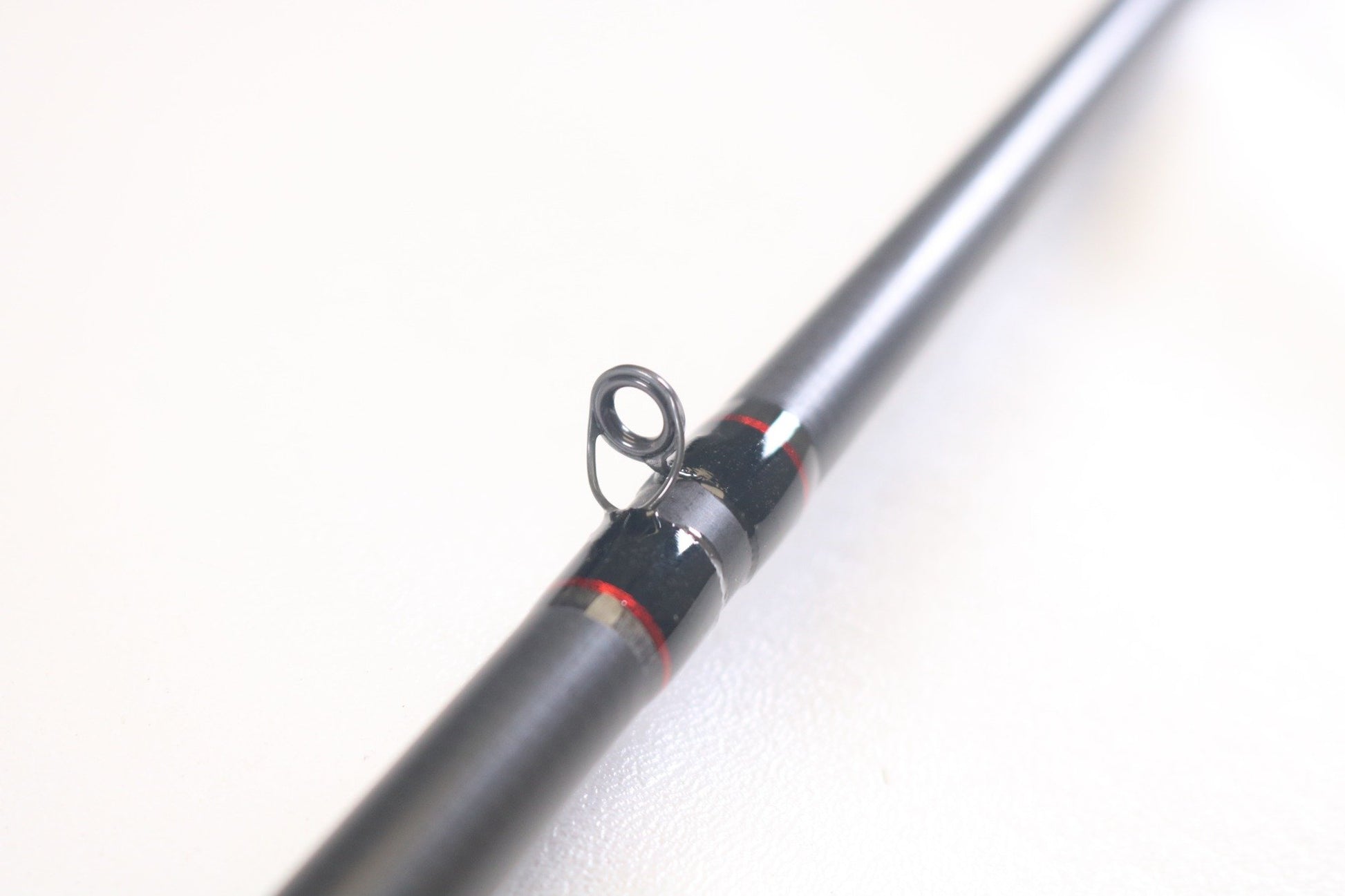 Close-up of a Hammer Rods Micro Guide Flipping 7'9" Heavy casting rod from our trade-in program, with metallic accents and red detailing near the guide. The sleek black design pops against a white background. Exchange your used gear for store credit today!.