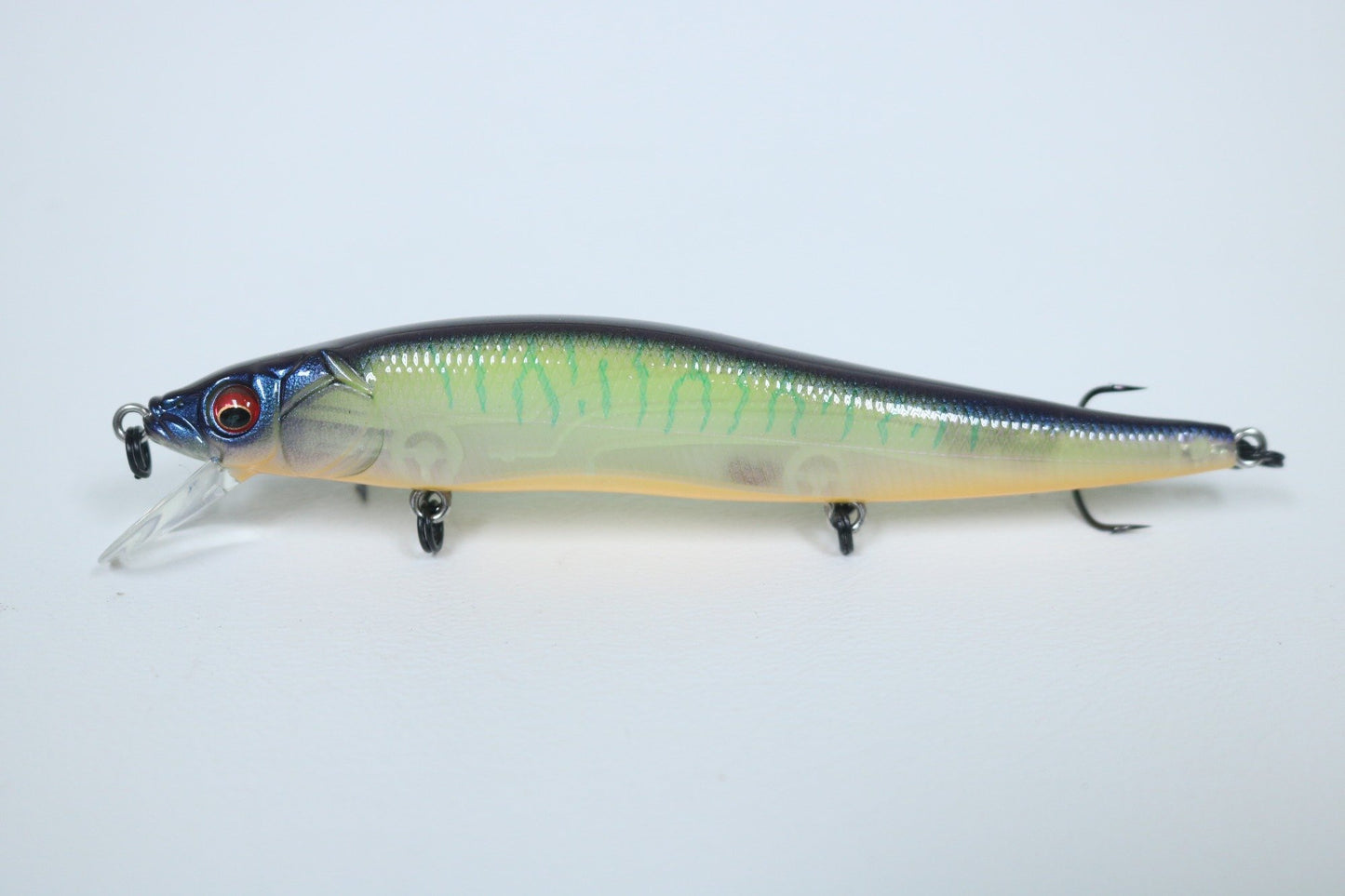 The Megabass Vision 110 Jerkbait by Megabass is a meticulously crafted fishing lure featuring a vibrant, multicolored finish. Its translucent body showcases shades of green, black, and yellow. It is equipped with Katsuage Out-Barb Trebles and lifelike eyes. The VISION ONETEN jerkbait is set against a simple white background.