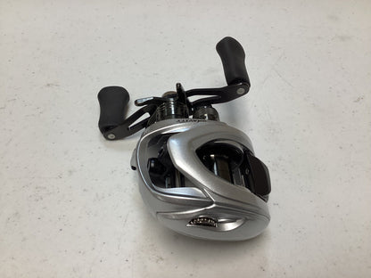 The Ark Gravity 7 G7107 Reel, in excellent condition with silver finish and black handles, is ready on a white surface for the Rod and Reel Trade-In program where used gear can earn valuable store credit.