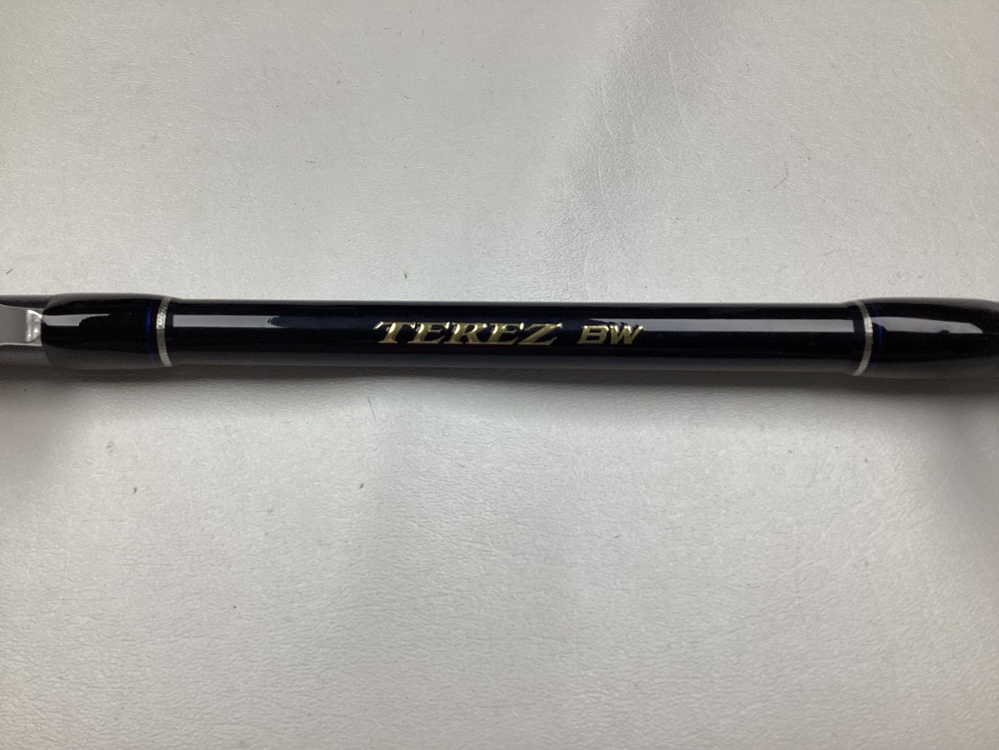 A Shimano Terez BW Full Roller Uni Butt Rod, 78" in black and silver with "TEREZ BW" inscribed in gold on a light gray background—ideal for our Rod and Reel Trade-In Program. Used but in mint condition.