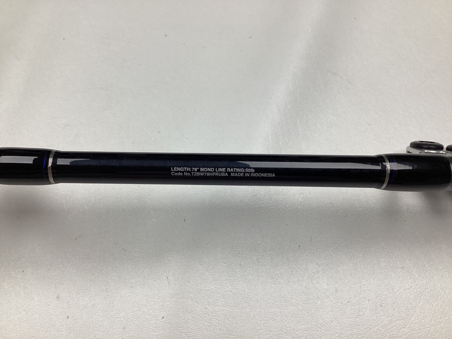 A black Shimano Terez BW Full Roller Uni Butt Rod, 78" long, made in Indonesia, rests on a white surface. In mint condition and great for Rod and Reel Trade-In opportunities, this used heavy-duty gear is perfect for enthusiasts.