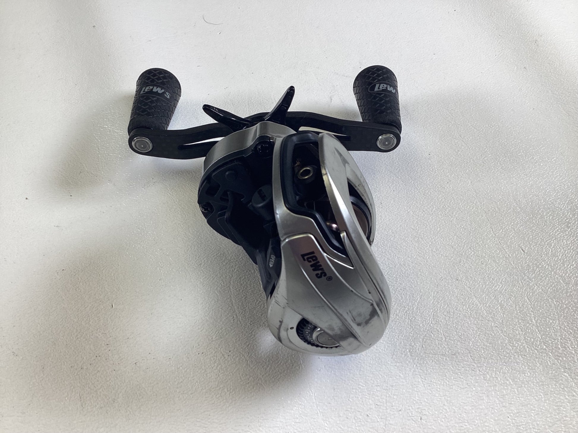 A Lew’s HyperMag TLH1SHG2 7.5:1 RH casting reel, in good used condition, features a sleek silver design with two black textured handles on a white surface. Consider trading it in the Rod and Reel Trade-In Program for store credit.