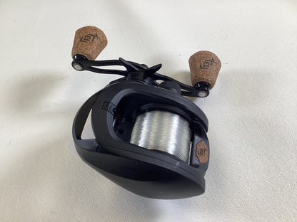 A used 13 Fishing Concept A3 Gen II CA3-8.1-RH casting reel in excellent condition, featuring dual brown cork handles and transparent line, sits on a white surface, perfect for a Rod and Reel Trade-In.