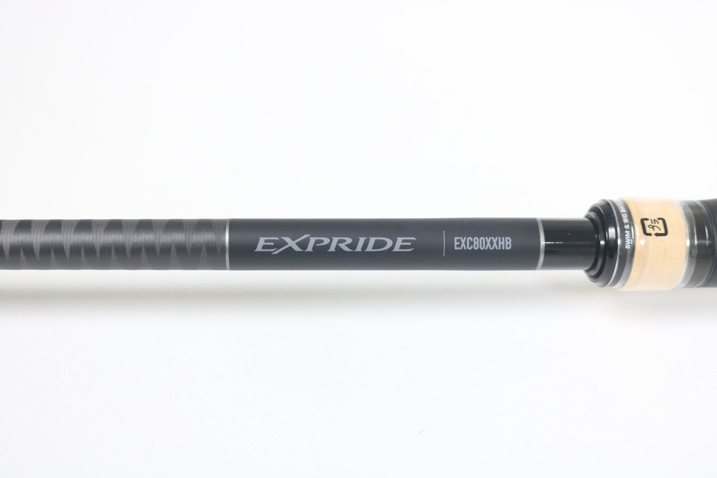 Close-up of a Shimano Expride B EXC80XXHB 8'0" XXH, a mint condition used casting rod. The black shaft highlights "Expride" and "EXC80XXHB," ideal for our Rod and Reel Trade-In Program. It features a light wood handle with a textured grip against a white backdrop.