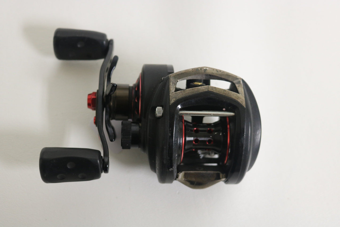 The Abu Garcia Revo SX RVO3 SX-HS-L 7.1:1 LH Casting Reel, featured in black and red with a dual handle grip and smooth metallic finish, is pictured on a white background, showcasing its visible internal components and spool—ideal for the Rod and Reel Trade-In Program.