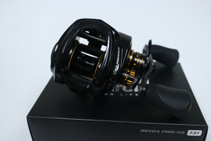 The Abu Garcia Revo Premier Gen 4, a black and gold baitcasting reel with dual handles, rests elegantly on a dark box labeled "REVO4 PRM-HS 7.3:1," ideal for upgrading your gear through our Rod and Reel Trade-In Program using store credit.