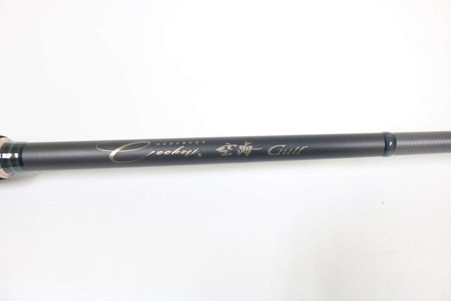 A close-up of a Megabass Cookai Gulf CKG-70M+S 7'0" spinning rod in excellent condition, labeled with "Megabass Cookai Gulf," featured in our Rod and Reel Trade-In Program. The rod rests against a plain white background, ready for its next adventure.