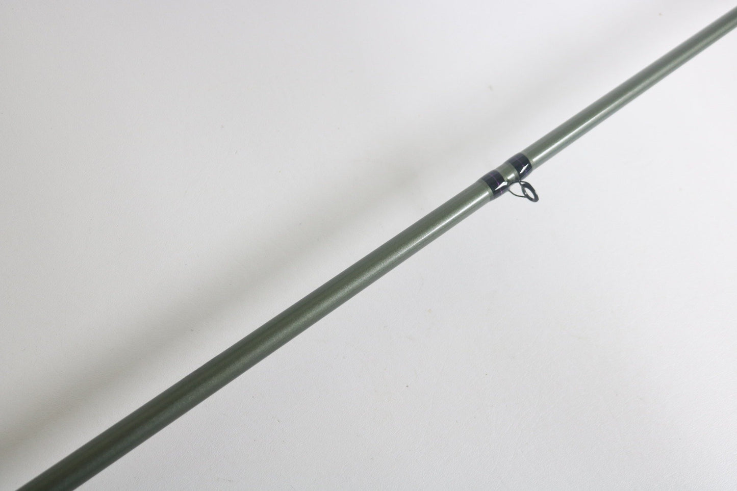 A St. Croix Mojo Bass MGC72MM used casting rod in excellent condition, part of our Rod and Reel Trade-In Program, lies diagonally on a white surface. It features a black guide loop near the middle, ideal for upgrading your gear with store credit.