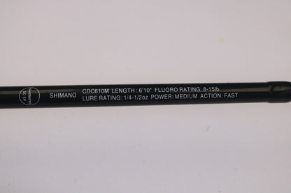 Get a close-up of the Shimano Curado CDC610M 6'10" Medium casting rod: Fluoro Rating of 8-15lb, Lure Rating of 1/4-1/2oz, Power Medium, Fast Action. Its sleek black design with white text could be your perfect catch—consider our Rod and Reel Trade-In Program to upgrade used gear.