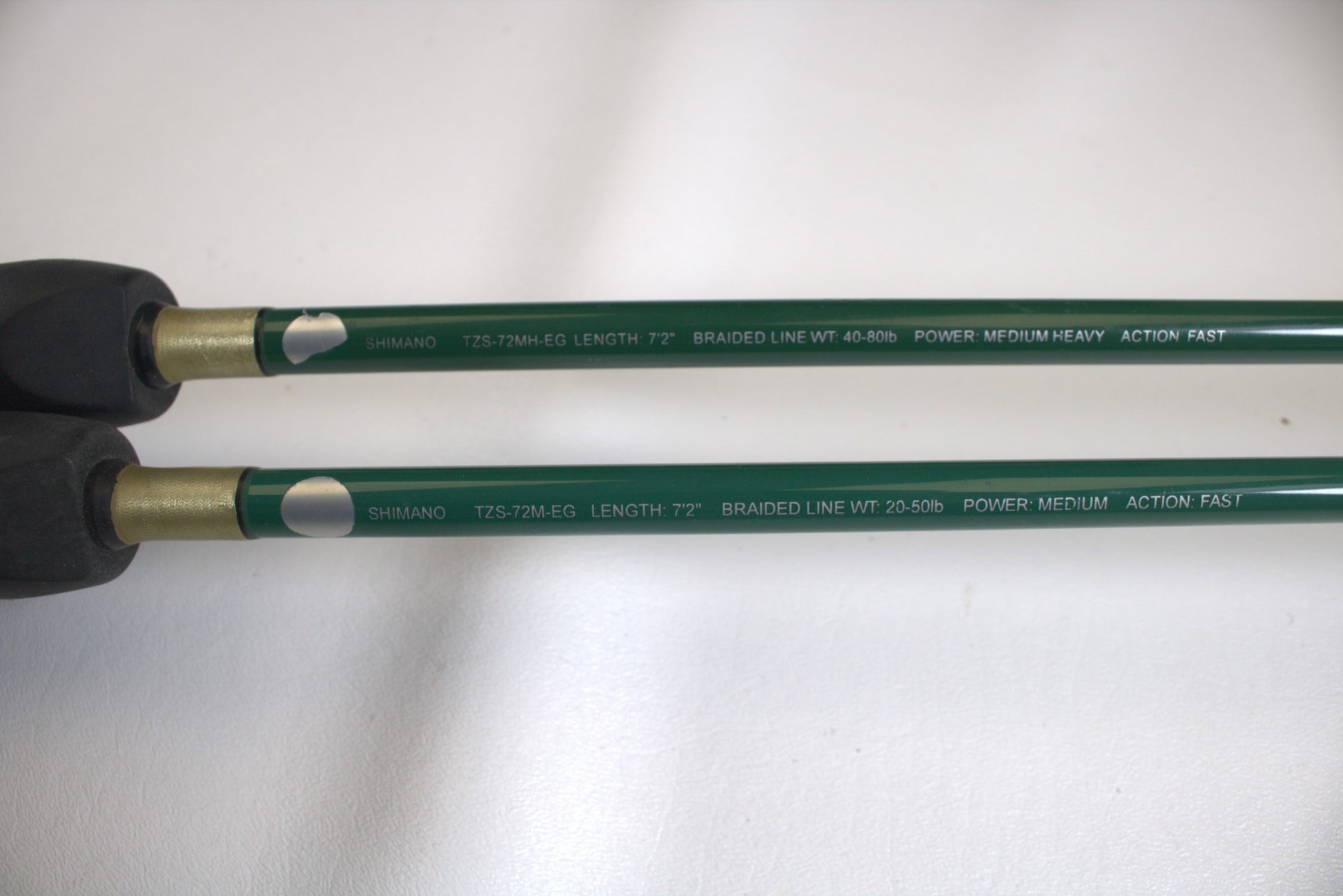 Close-up of two green Shimano Terez Evergreen rod handles showing specifications: "Shimano," lengths "7'2"," braided line weights "40-65lb" and "20-50lb," actions "Fast" and "Medium Heavy," and featuring black grips.