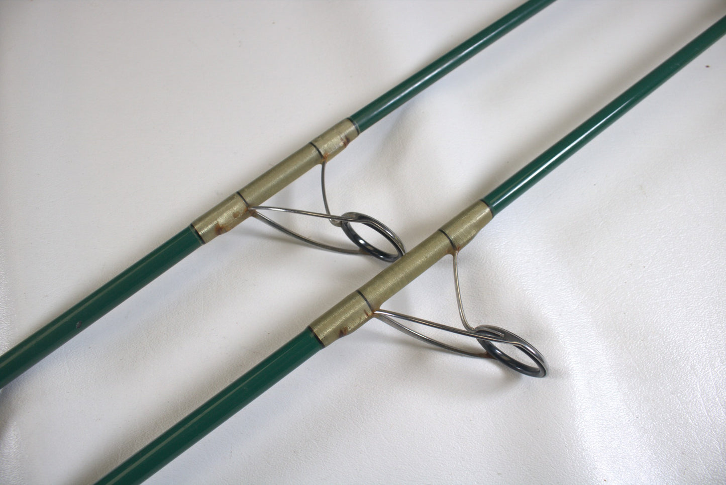 Two Shimano Terez Evergreen spinning rod sections, each showcasing metal line guides and joined by brass fittings, rest on a white surface.