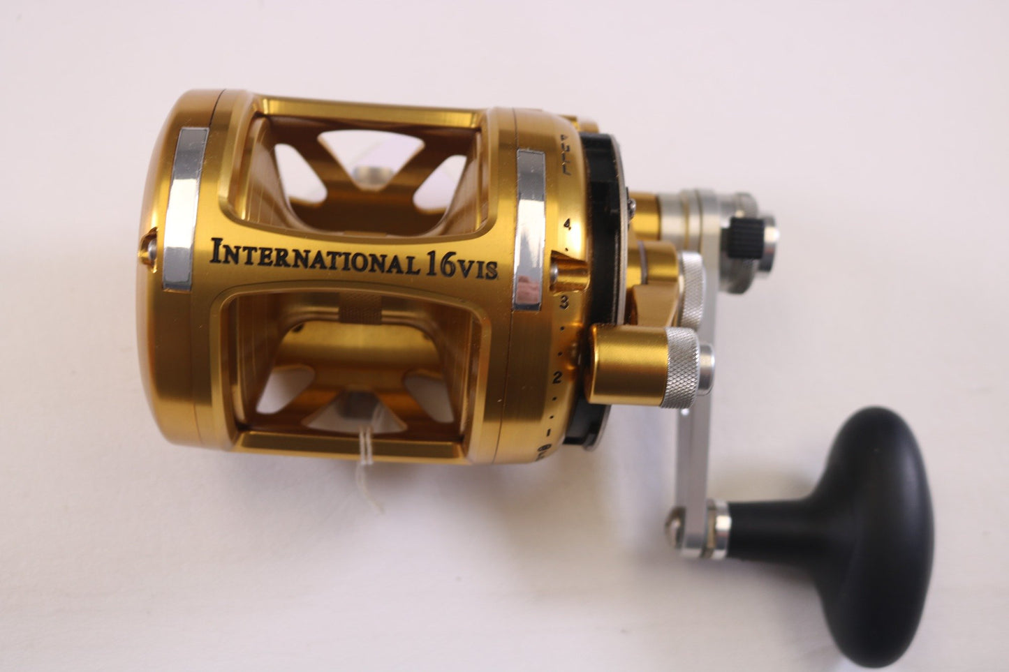 Close-up of Penn's gold "International VI INT16VIS" used casting reel in mint condition on a white background. Ideal for those interested in our Rod and Reel Trade-In Program, it showcases a black handle and silver adjustment knobs.