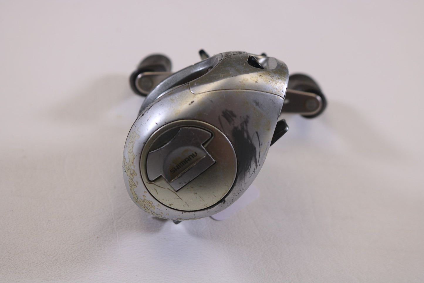 A close-up of a worn Shimano Chronarch 51Mg 6.2:1 LH casting reel in fair condition, part of our used gear collection, against a white background. The reel's handle and mechanisms show use and age, ideal for those seeking store credit through trade-in.