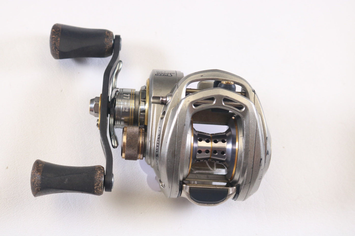 Displayed on a pristine white background, the Lew's Team Lew's Lite TLL1SHL 7.5:1 LH features silver with black handles, a metal frame with intricate cutouts, and is an excellent example of quality used gear for enhancing collections through our Rod and Reel Trade-In Program.